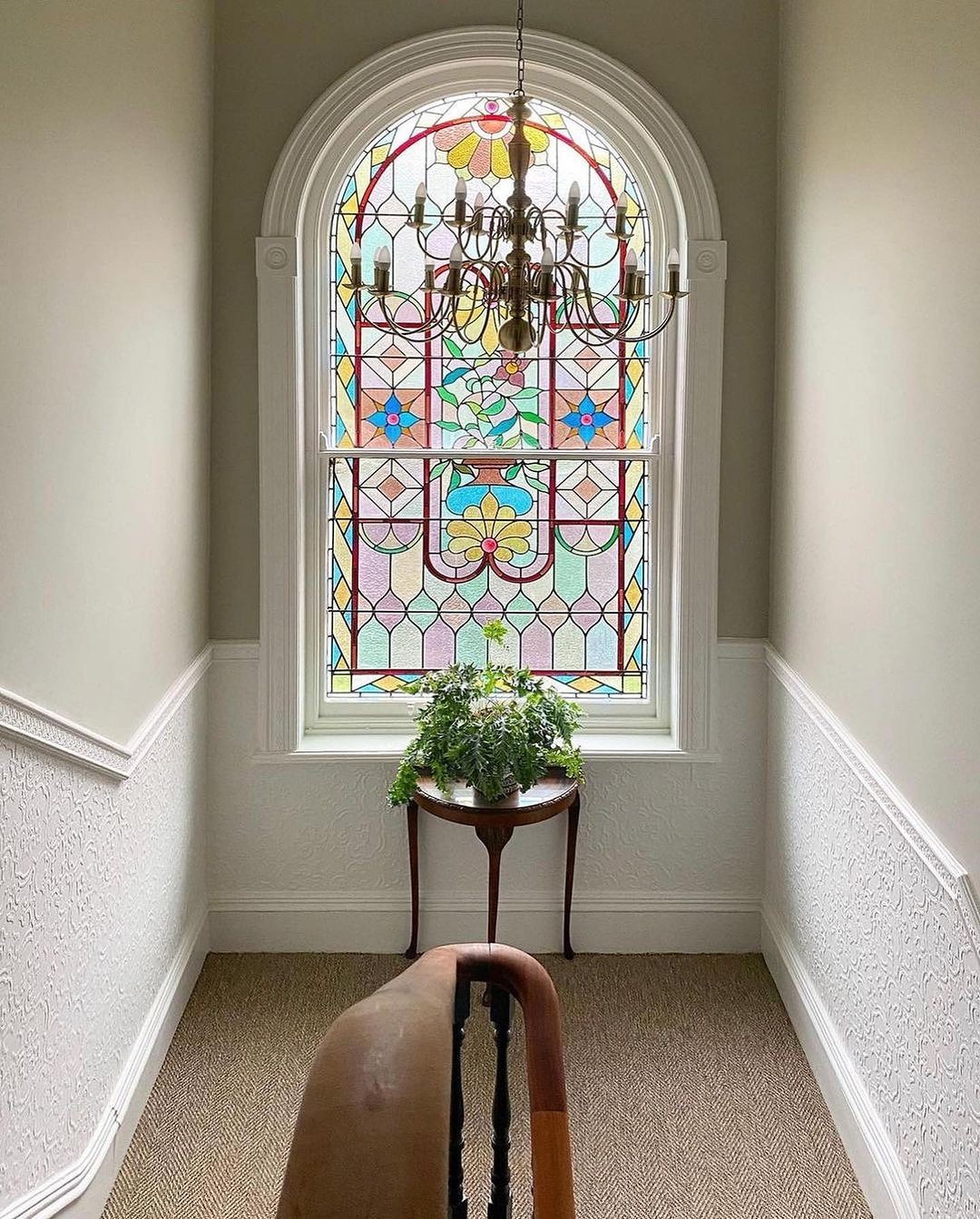 Restored arched stained glass window on heritage staircase landing Belfast